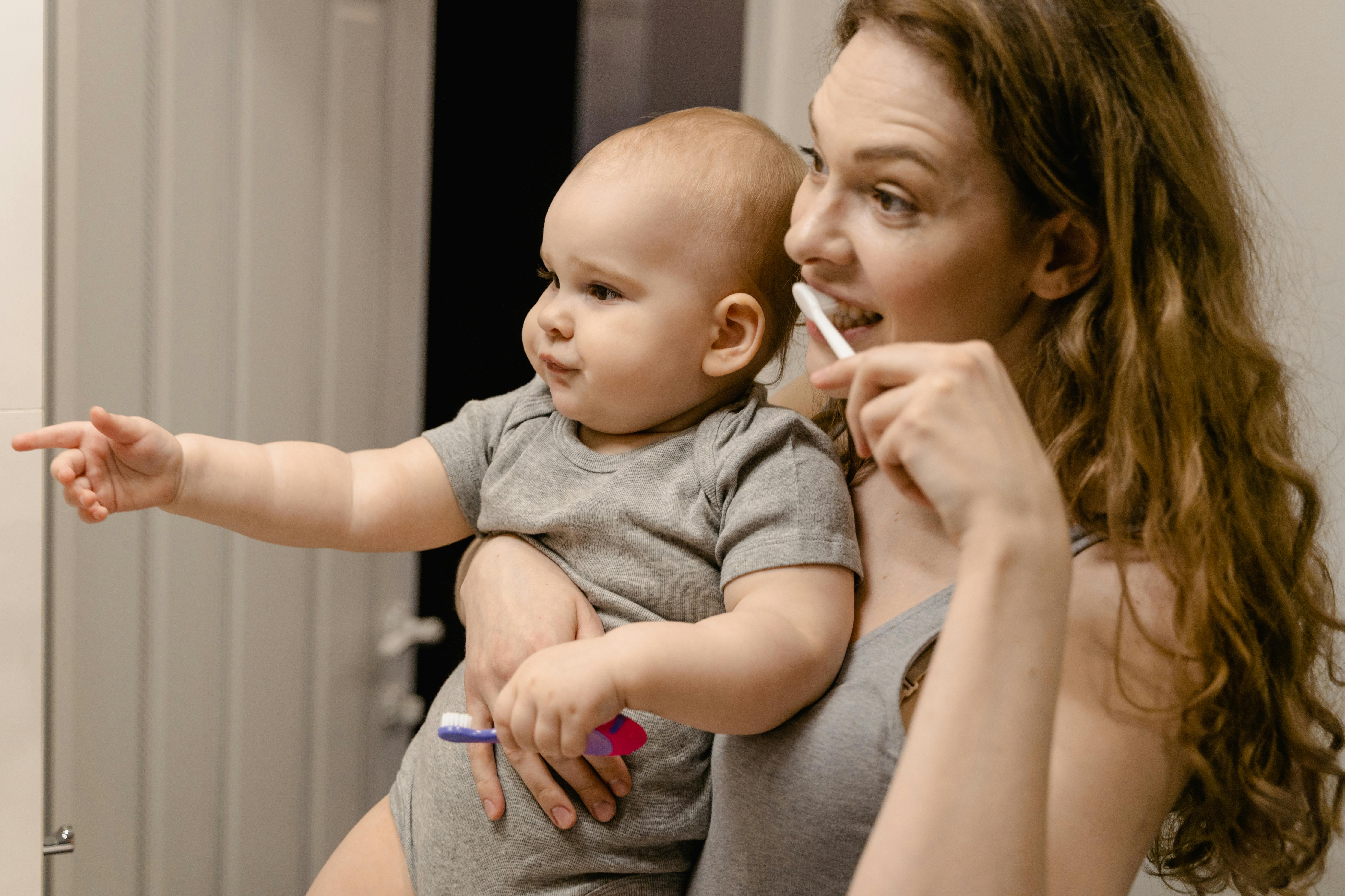 A joyful moment as a mother teaches her baby toothbrushing, fostering healthy habits.