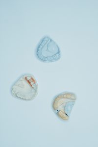 Three dental molds displayed on a blue background in a top-view vertical shot.